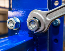 Wrench is tightening the chrome  nut on the blue metal folding shelf