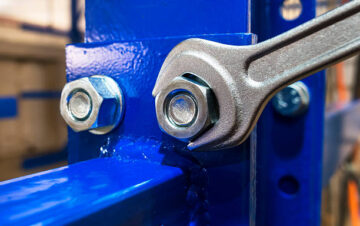 Wrench is tightening the chrome  nut on the blue metal folding shelf